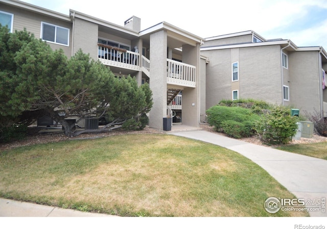 rear view of property with stairs, a yard, a chimney, and stucco siding