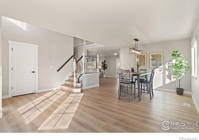 dining area featuring a healthy amount of sunlight, a notable chandelier, and light hardwood / wood-style floors