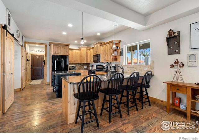 kitchen with black appliances, a kitchen bar, hanging light fixtures, kitchen peninsula, and a barn door