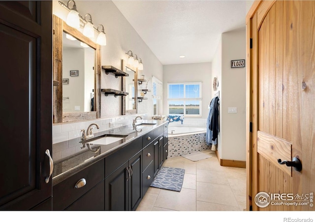 bathroom with tasteful backsplash, a textured ceiling, vanity, a relaxing tiled tub, and tile patterned flooring