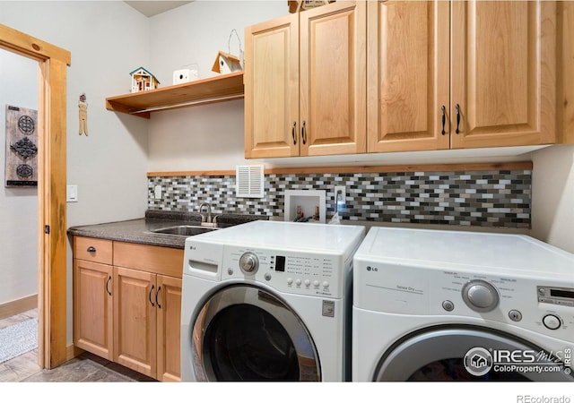 washroom featuring cabinets, sink, and washing machine and clothes dryer