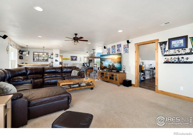 carpeted living room with a textured ceiling and ceiling fan