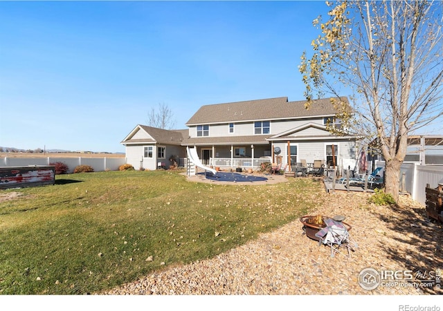 rear view of property featuring a lawn, a patio area, and an outdoor fire pit