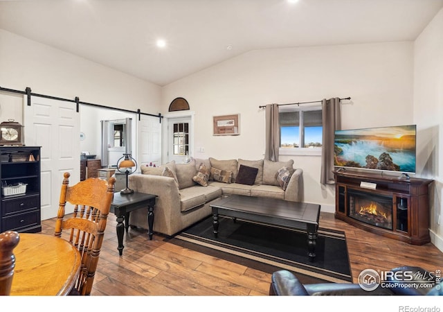 living room featuring hardwood / wood-style flooring, a barn door, and lofted ceiling