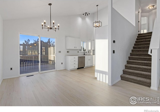 interior space with light wood-type flooring, high vaulted ceiling, sink, and a notable chandelier