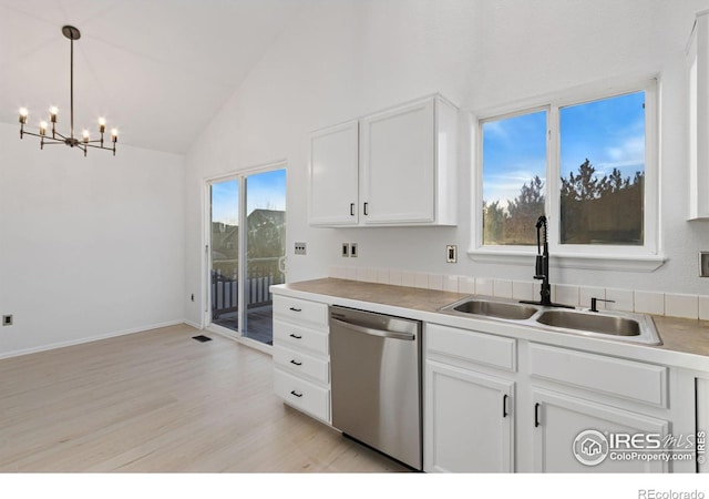 kitchen featuring pendant lighting, white cabinetry, lofted ceiling, sink, and stainless steel dishwasher