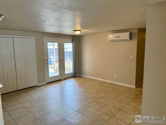 interior space featuring a textured ceiling, a wall mounted air conditioner, and baseboards