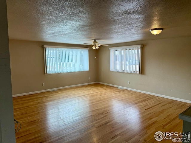 spare room with a textured ceiling, light wood finished floors, a ceiling fan, and baseboards