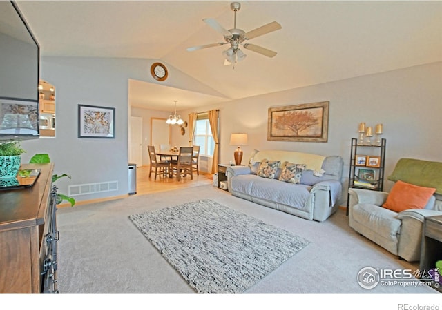 carpeted living room with ceiling fan with notable chandelier and vaulted ceiling