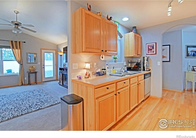 kitchen featuring stainless steel dishwasher, sink, light brown cabinets, light hardwood / wood-style floors, and lofted ceiling