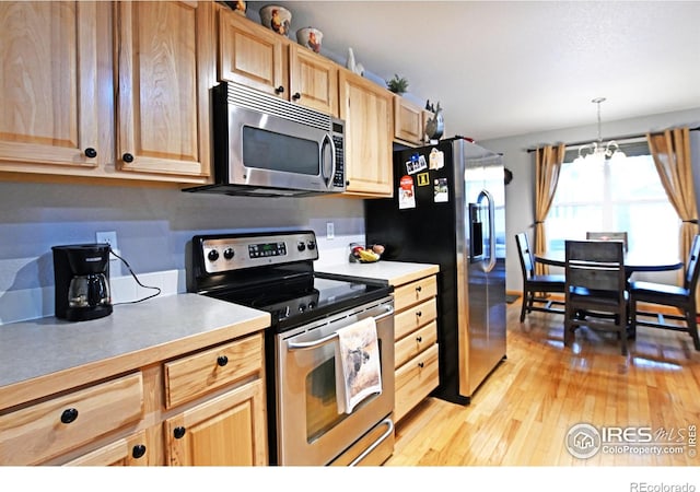 kitchen featuring a chandelier, light hardwood / wood-style flooring, stainless steel appliances, and decorative light fixtures