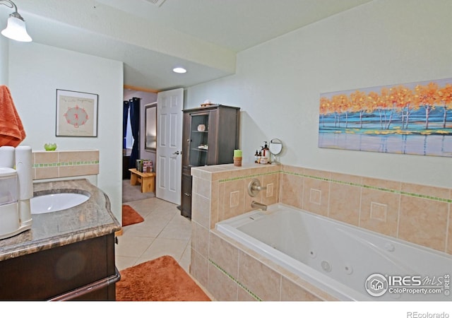 bathroom with tiled tub, tile patterned flooring, and vanity