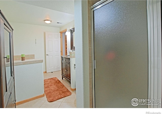 bathroom featuring tile patterned floors, vanity, and a shower with door