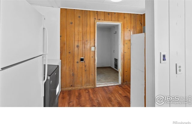 kitchen with white refrigerator, dark hardwood / wood-style flooring, and wooden walls