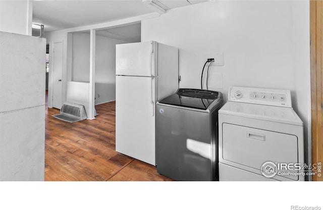 clothes washing area with washing machine and dryer and dark hardwood / wood-style flooring