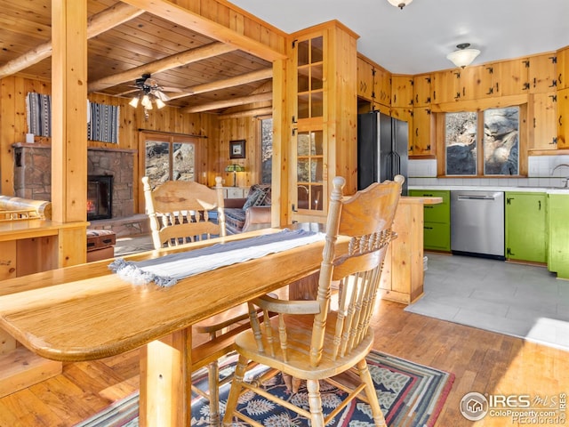 dining room featuring a healthy amount of sunlight, wooden ceiling, beamed ceiling, a fireplace, and light wood-type flooring