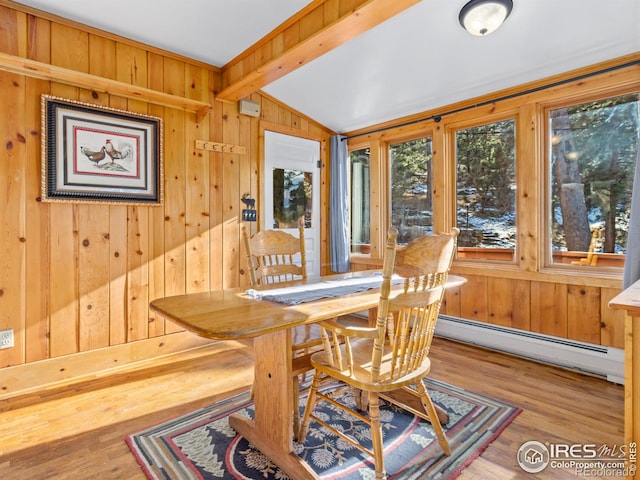 dining area featuring wood walls, wood-type flooring, lofted ceiling with beams, and a baseboard heating unit