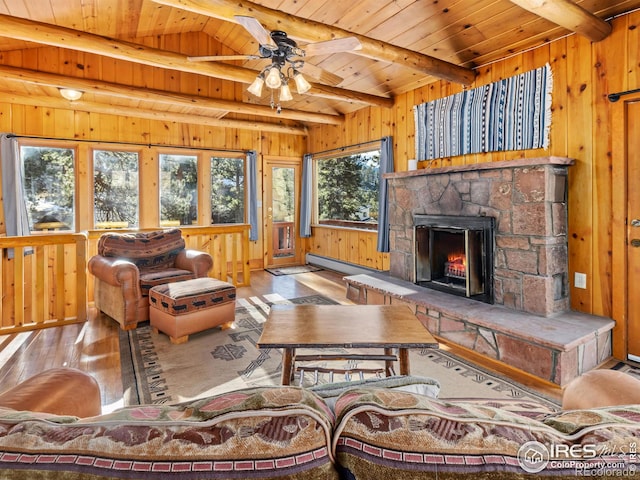 living room featuring wooden walls, a fireplace, beamed ceiling, light hardwood / wood-style floors, and wood ceiling