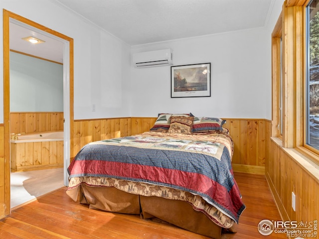 bedroom featuring wood walls, wood-type flooring, crown molding, and a wall unit AC