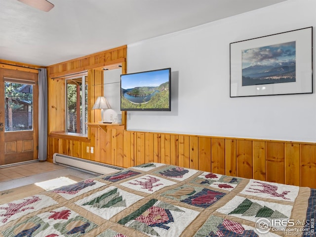 bedroom with baseboard heating, ornamental molding, and wood walls