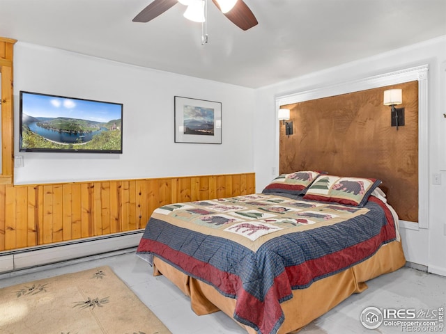 bedroom featuring baseboard heating, ceiling fan, and wood walls