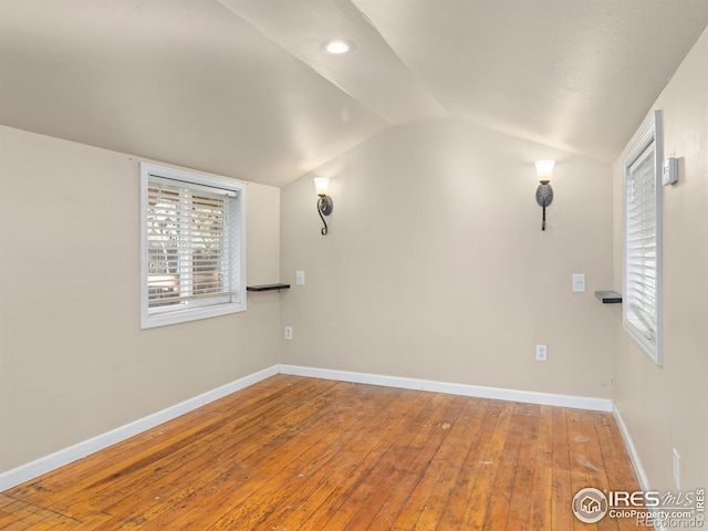 spare room with hardwood / wood-style floors and lofted ceiling