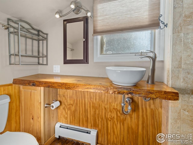 bathroom featuring toilet, vanity, and a baseboard heating unit