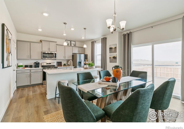 dining space featuring a healthy amount of sunlight, an inviting chandelier, sink, and light hardwood / wood-style flooring