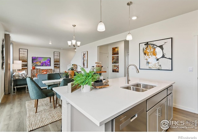 kitchen with dishwasher, sink, dark hardwood / wood-style floors, an island with sink, and decorative light fixtures