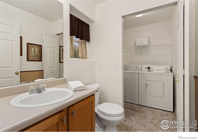 bathroom featuring vanity, washing machine and dryer, and toilet