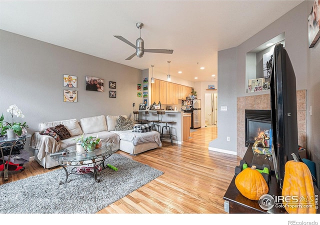 living room featuring a fireplace, light hardwood / wood-style floors, and ceiling fan