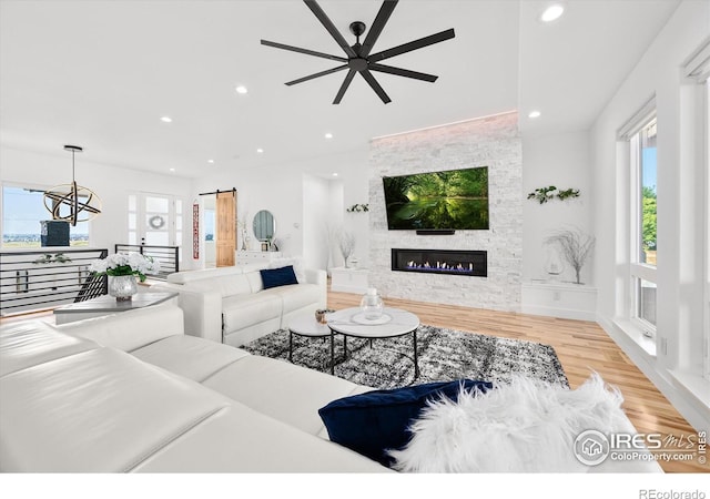 living room featuring a fireplace, light hardwood / wood-style floors, a wealth of natural light, and ceiling fan