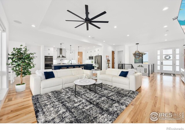 living room featuring light hardwood / wood-style flooring, ceiling fan, and sink