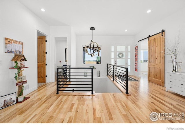 stairs with a barn door, hardwood / wood-style flooring, and an inviting chandelier