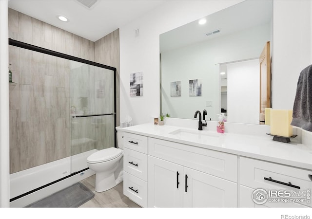 bathroom with vanity, hardwood / wood-style flooring, toilet, and walk in shower