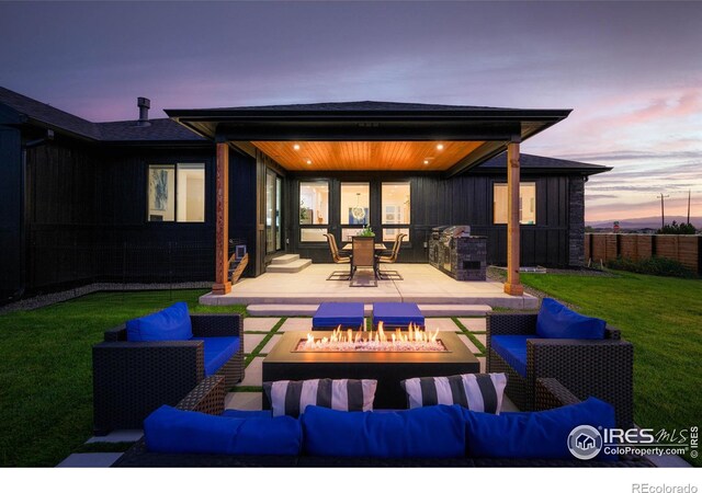 patio terrace at dusk with a lawn and an outdoor living space with a fire pit