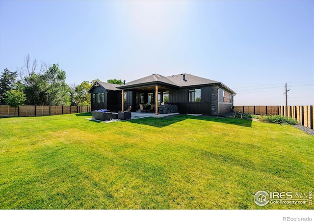 back of house featuring an outdoor living space, a patio, and a lawn