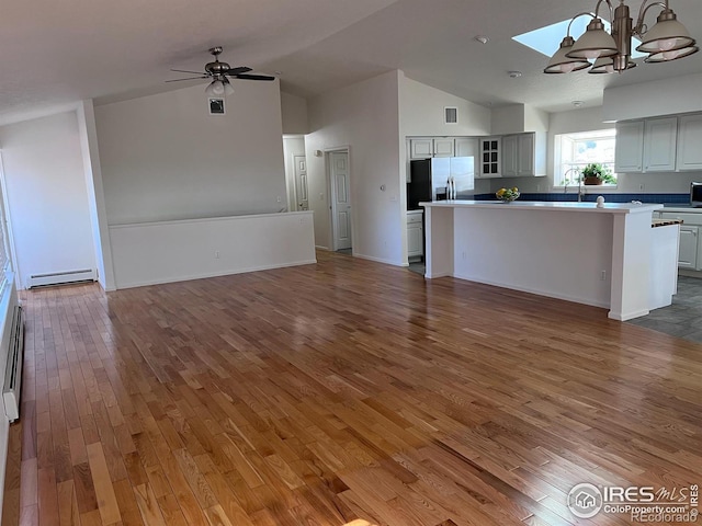 kitchen with vaulted ceiling, a kitchen island, hanging light fixtures, dark wood-type flooring, and stainless steel fridge with ice dispenser