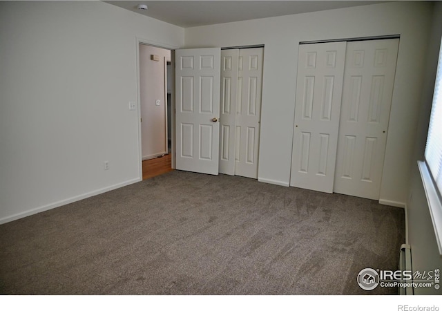 unfurnished bedroom with dark carpet and two closets