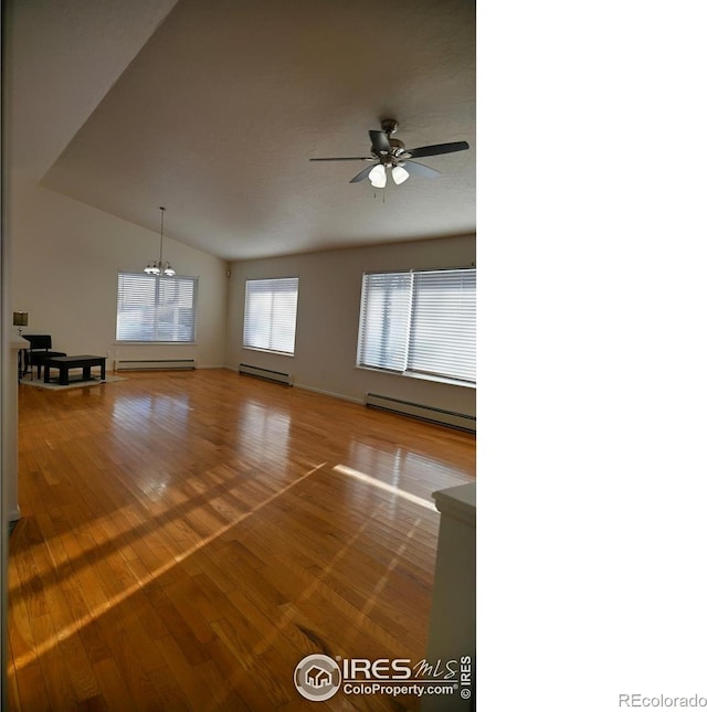 spare room featuring baseboard heating, vaulted ceiling, and hardwood / wood-style flooring