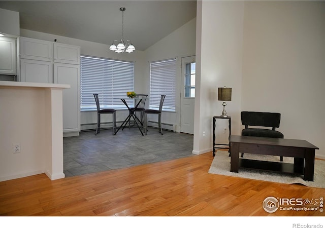 dining room featuring vaulted ceiling, a baseboard heating unit, an inviting chandelier, and light wood-type flooring