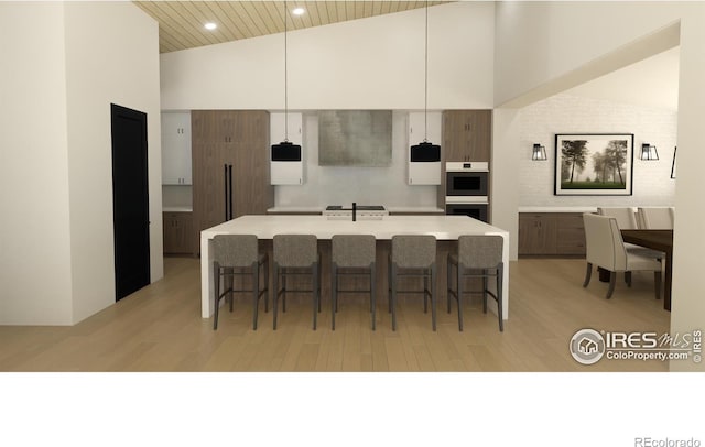 kitchen featuring an island with sink, double oven, and light hardwood / wood-style flooring