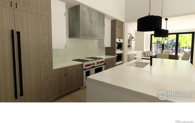 kitchen with tasteful backsplash, wall chimney exhaust hood, luxury range, sink, and decorative light fixtures