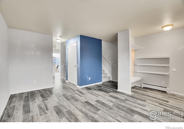 empty room featuring baseboard heating and hardwood / wood-style floors