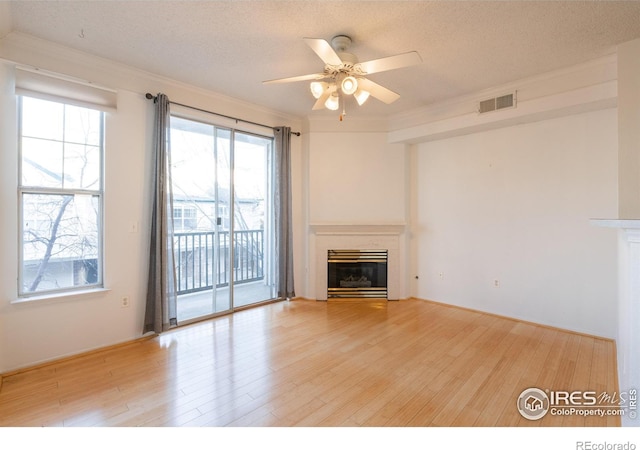 unfurnished living room with plenty of natural light, light hardwood / wood-style floors, and a textured ceiling