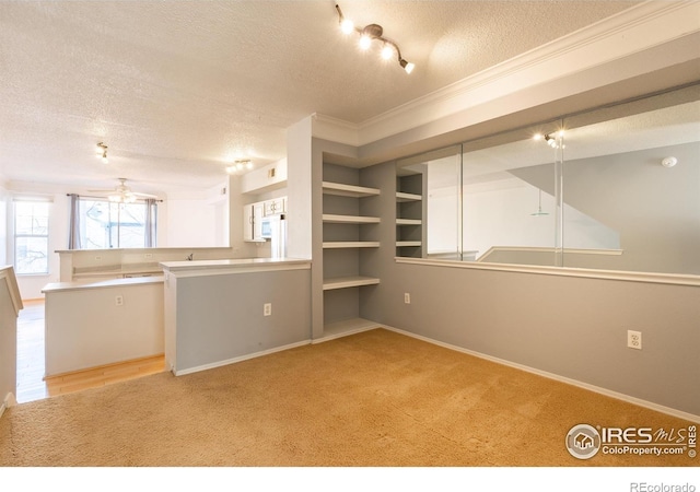 kitchen featuring light carpet, kitchen peninsula, a textured ceiling, ceiling fan, and crown molding