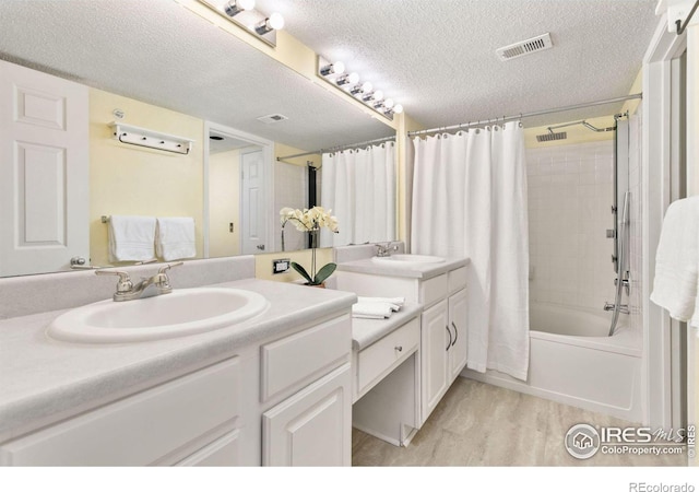 bathroom featuring hardwood / wood-style floors, vanity, a textured ceiling, and shower / tub combo