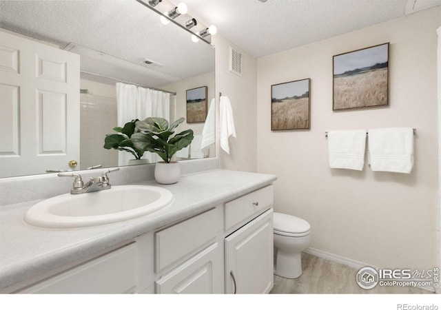 bathroom featuring a textured ceiling, vanity, toilet, and curtained shower