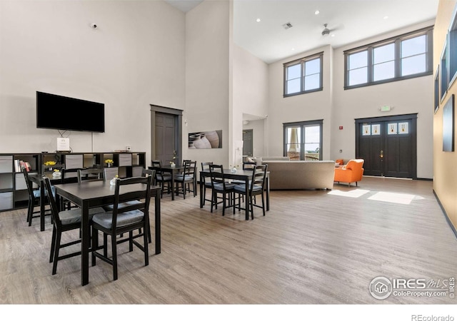 dining room featuring light hardwood / wood-style floors and a high ceiling