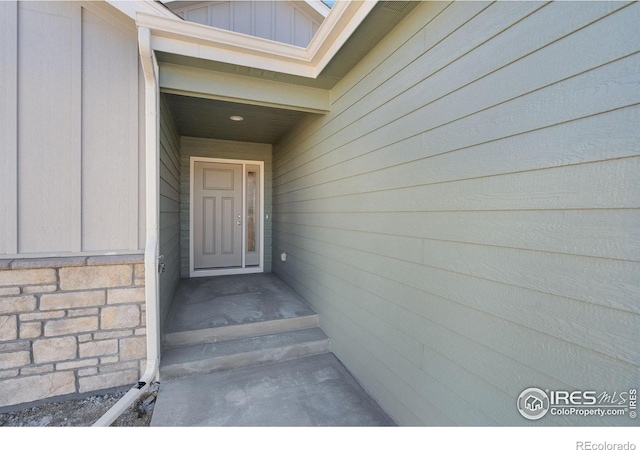 property entrance featuring stone siding and board and batten siding